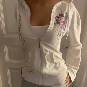 2000s Ed Hardy kofta  -  vintage kofta från Ed Hardy med rhinestones och tryck. Storlek XL men sitter som en S/M. Enda defekt är en liten fläck på insidan som inte syns utanpå alls (bild 4) 
