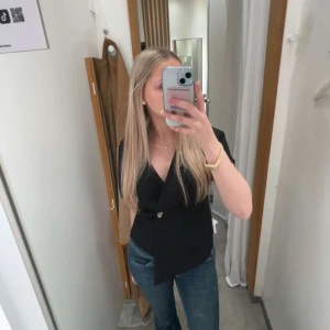 Svart omlottopp med v-ringning - Snygg svart omlottopp med v-ringning och korta ärmar. Jag köpte den för 3 dagar sedan och den släpptes i butik för 4 dagar sen! Den är super fin festlig eller ba allmän topp men tror inte jag kommer använda så mycket..