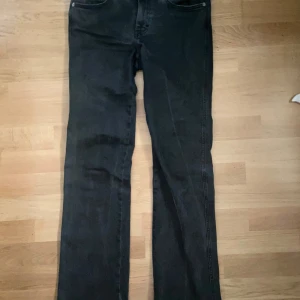 Svarta 90's bootcut jeans 157 - Svarta jeans från 157 med bootcut-silhuett inspirerad av 90-talet. Klassisk femficksmodell med snygga detaljer på bakfickorna och knappstängning framtill. Jeansen är i ett stretchigt denimtyg som sitter skönt och ger en retro vibe. De är i storlek S full length