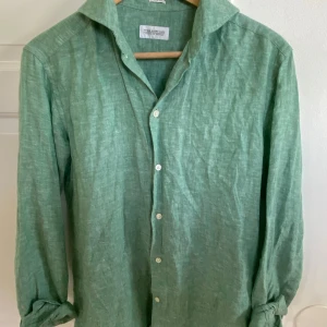 Grön linneskjorta, These Glory Days - En väldigt skön, bekväm och stilren linneskjorta som köptes förra året. Användes sällan, bara några fåtal gånger. Storlek: S 37/38 och märket är THESE GLORY DAYS - tribute to bespoke. Köp denna om du vill känna dig lite extra fräsch i sommar!