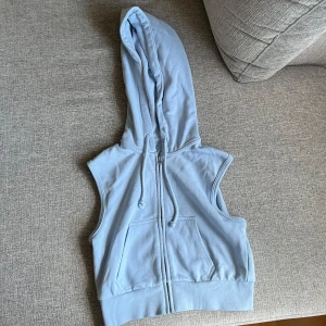 Ljusblå hoodie-väst från H&M Divided XS - Ljusblå ärmlös hoodie-väst från H&M Divided i storlek XS. Västen har dragkedja framtill, två fickor och en stor huva med dragsko. Perfekt för lager-på-lager och chill stil.😙