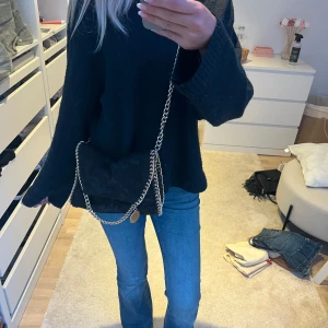 Svart axelväska med kedja - Säljer en svart stellamccartneyliknande väska med guldkedja. Litet fack på insidan. En liten tråd är lös på framsidan men man kan bara peta in den så ser den ut som ny. Använd några gånger varsamt 