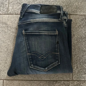 Replay Jeans - Snygga Replay Anbass jeans i mörkblå tvätt med klassiska kontrastsömmar och bakficka med broderad detalj. Modellen har rak passform och är tillverkad i mjukt jeanstyg som sitter skönt hela dagen.