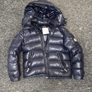 Mörkblå Moncler pufferjacka med huva - Hej. Jag säljer min monclear jacka för 2500 kr. Jag köpte den på babyshop för ca 6 000 kr år 2022. Jag har använt den hela vintern 2022-2023 och sedan ett par gånger 2023-2024 vintern. Den är i väldigt gott skick, inga märken, inga hål, absolut inga fel på den och den är jätte fräsch. Den funkar både för kvinnor/flickor och män/pojkar som har storlek xs. Testa och titta på den innan köp är okej. Anledningen till att jag säljer den är för att jag har ont om pengar och behöver pengar så fort så…