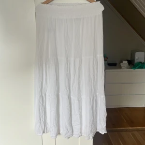 Vit långkjol från 157, storlek M - Säljer en flowy vit långkjol från 157 i storlek M. Kjolen har smockad midja för extra komfort och är tillverkad i 100% viskos, vilket gör den superlätt och luftig. Perfekt för varma dagar när du vill ha en chill och stilren look. 50 + frakt priset kan diskuteras 