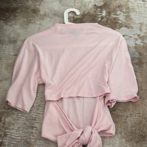 Ljusrosa omlottopp från Gina Tricot - Supersöt ljusrosa omlottopp från Gina Tricot med knyt baktill. Storlek xs använd ett fåtal gånger.