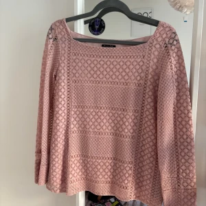 Rosa spetsblus från Massimo Dutti - Superfin ljusrosa blus i spets från Massimo Dutti. Blusen har lång ärm, fyrkantig ringning och ett detaljerat spetsmönster över hela plagget. Perfekt för dig som gillar romantisk och feminin stil. Snygg att styla med jeans eller kjol.