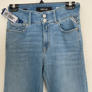 Replay ljusblå bootcut flare jeans - Snygga ljusblå jeans från Replay i bootcut/flare-modell. Jeansen har klassisk femficksdesign, dragkedja och knappar framtill samt detaljerad bakficka. Tillverkade i hållbar bomull för en skön känsla och stilren look. Ny, etiketten är kvar. 