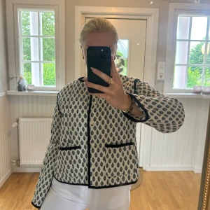 Mönstrad quiltad jacka i vitt och svart - Säljer en supertrendig quiltad jacka från HM i vitt med svart mönster och svarta detaljer. Jackan har rund hals, knappar framtill och två stora fickor. Storlek M men sitter mer som en S.💖💖använd en gång endast.