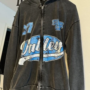 Svart hoodie med blått Valley-tryck - Svart hoodie med dragkedja och huva, stora blå och vita tryck fram och bak med texten 'Valley', '07' och 'Factor Glory'. Oversized passform och långa ärmar. Super Unisex