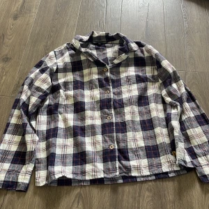 Rutig skjorta från Pernilla Wahlgren - Snygg rutig skjorta från Pernilla Wahlgren i blått, vitt och rött. Skjortan har klassisk krage, knäppning framtill och långa ärmar. Perfekt för en chill och avslappnad stil. Tillverkad i mjuk bomull som känns skön mot huden.