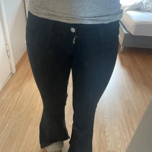 Svarta bootcut jeans med stretch - Säljer ett par svarta bootcut jeans med snygg passform och stretchigt material. Byxorna har klassiska fickor fram och bak, samt en liten detalj med rosa brodyr på bakfickan. Perfekta för dig som gillar en tidlös look med lite utsvängda ben. Er weekday byxor