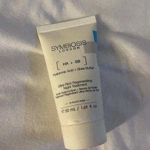 Symbiosis London nattkräm 50 ml - Ultra-Rich Regenerating Night Treatment med hyaluronsyra och sheasmör. Vit tub med svart text, 50 ml. Perfekt för dig som vill boosta huden med fukt och näring under natten. Vegansk och cruelty free.