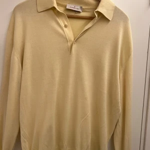 Beige pikétröja från Ermenegildo Zegna - Klassisk beige pikétröja från Ermenegildo Zegna i mjuk stickad bomull. Tröjan har lång ärm, krage och knäppning med tre knappar framtill. Perfekt för dig som gillar en clean och stilren look med premiumkänsla. Liten defekt då en av knapparna är av på mitten, går att sy på nya enkelt. Nypris ca 4000kr