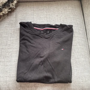 Svart t-shirt från Tommy Hilfiger - Svart t-shirt från Tommy Hilfiger med klassisk v-ringning och liten broderad logga på bröstet. Bara höra av er vid minsta frågor, pris kan diskuteras!🍾🤗