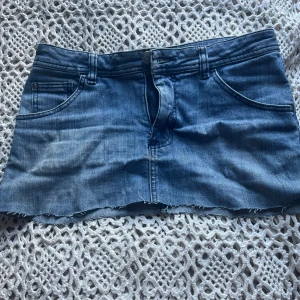 Blå jeanskjol från H&M med rå kant - Säljer en blå jeanskjol från H&M! Passar mig som är 163 lång och har storlek xs/s men lite stor