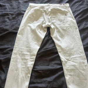 Dondup George 34 - Säljer ett par vita jeansbyxor från. Byxorna har diskreta sömmar och en liten metallogo på bakfickan. Perfekta för en stilren look. 