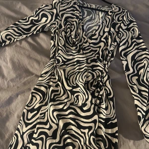 Svartvit omlottklänning med zebramönster - Säkjer min klänning då jag inte haft någon användning till den! Nytt skick knappt använd köptes förra året. Den är i storlek S men passar M