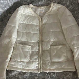 Vit jacka från Gina Tricot - Säljer en vit jacka från Gina Tricot. Jackan har rund hals, knappar framtill, två fickor och dekorativa stickade detaljer längs kanterna. Används ett fåtal gånger men är som ny! 🌸🩷 (köpt för 430kr)