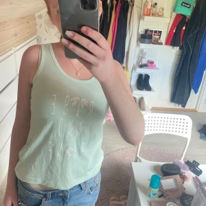 Mintgrön linnetopp från Turkiet - Säljer en mintgrön linnetopp från Red & Blue med tryck framtill och tjocka band, Toppen är i mjuk bomull och har en avslappnad passform, perfekt för varma dagar.