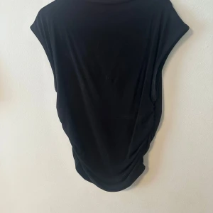 Svart ärmlös topp från Gina Tricot - En enkel svart ärmlös topp från Gina Tricot i mjukt material. Modellen är rak och har en klassisk rund halsringning. Kommer inte till användning och har för många såna här😊