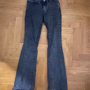 Grå/svarta bootcut jeans  - Säljer ett par jättefina low bootcut jeans från Gina tricot. I strl 32! Köpta för 500kr säljer för 349kr! Använda några fåtal gånger! Inga tydliga defekter på användning.