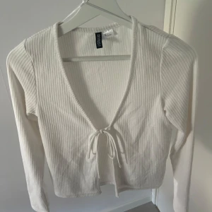 Vit ribbad knyt-topp  - Säljer en vit ribbad topp med lång ärm och v-ringning. Perfekt att styla med jeans eller kjol.💗