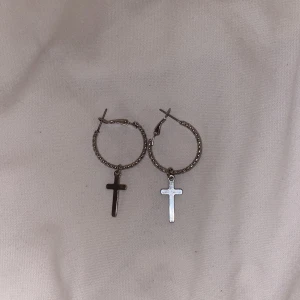 Silver armband och örhängen med kors  - Säljer ett armband med en kedja i silverfärg och ett stort kors som hänge, synligt använd. Och ett par örhängen med kors hängande på, aldrig använda.
