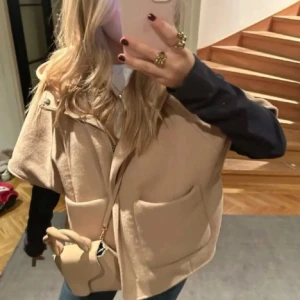 Beige ponchoväst med dragkedja - Säljer en beige ponchoväst med dragkedja och stora fickor framtill.  Passar snyggt till jeans och är enkel att styla för olika tillfällen! Passar höst, vår och svala sommardagar!!! 