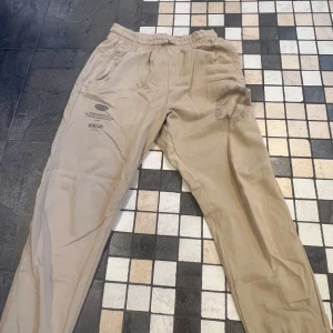 Beige mjukisbyxor från Gymshark - Beiga mjukisbyxor från Gymshark. Väldigt sköna att dels gymma i men också sätta på sig på kvällar och liknande, har en liten oversized fit 