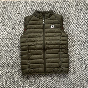 Olivgrön dunväst från JOTT - Säljer en olivgrön dunväst från JOTT. Västen har dragkedja framtill och står upp i kragen. Perfekt för lager-på-lager och enkel att matcha med olika outfits. Säljer den då den inte passar längre.