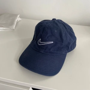 Mörkblå keps från Nike - Snygg mörkblå keps från Nike med klassisk vit broderad logga framtill. Justerbar baktill!
