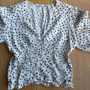 Vit blus med svarta prickar och volang - Säljer en söt vit blus med svarta prickar. Inga defekter, använd fåtal gånger. Storlek s🤗🤗