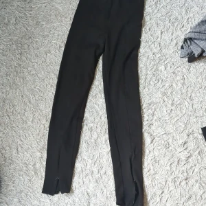 Svarta leggings - Svarta leggings med tight passform och slitsar nertill på benen (finns dragkedjor). Perfekta att styla med oversized tröjor eller hoodies. Mjukt och stretchigt material som sitter skönt hela dagen.