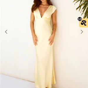 Balklänning  - Elegant ljusgul långklänning med v-ringning och öppen rygg. Klänningen har korta ärmar och är tillverkad i ett mjukt, flödande material som ger en vacker siluett. Endast testad.