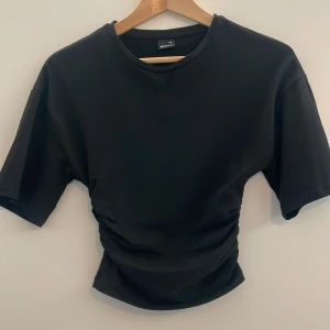 Svart croppad t-shirt med rynkade detaljer - Köpt i januari för 260 kr men den kommer knappt till användning (jag tror att jag har haft på mig den 2/3 ggr). ‼️frifrakt annons finns‼️