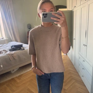 Beige stickad topp från & Other Stories - Säljer en beige stickad topp från & Other Stories. Tröjan har korta ärmar, rund halsringning och är i ett mjukt material. Perfekt att styla med jeans eller kjol för en enkel men snygg look.