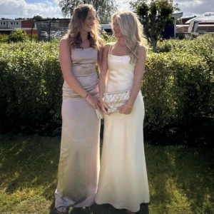 Champagnefärgad Balklänning - Balklänning, champagnefärgad satin med smala axelband. Justerbar då man knyter den i ryggen. Perfekt för bal eller festliga tillfällen.