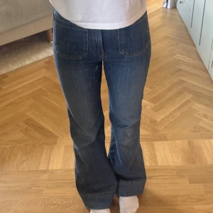 Blå bootcut jeans från Jeanerica - Säljer ett par klassiska blå bootcut jeans från Jeanerica, modell SW006 Vintage 62. Jeansen är tillverkade av ekologisk bomull med lite stretch och återvunnen polyester. Snygg passform med normal midja och utsvängda ben.