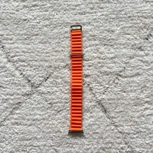 Orange klockarmband i textil - Säljer ett orange klockarmband i textil med ribbad struktur och metallspännen. Armbandet har en stark färg och passar till smartklockor med rätt fäste. Perfekt för dig som vill ge din klocka en färgklick.