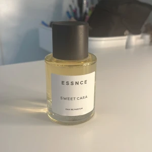 ESSNCE Sweet Cara Eau de Parfum - En stilren parfymflaska med transparent glas och svart lock. Innehåller en ljusgul Eau de Parfum med namnet Sweet Cara från ESSNCE. Flaskan har en minimalistisk etikett och en klassisk rund form. Lukten stannar kvar väldigt länge😍hör av dig vid frågor kan tänka mig att diskutera pris
