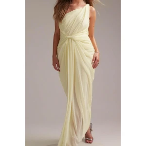 Gul draperad klänning - Elegant ljusgul långklänning med draperad design och omlottkänsla. Klänningen har en axel och markerad midja som ger en snygg siluett. Perfekt för bal eller festliga tillfällen. balklänning. St 40, från asos, helt slutsåld i alla storlekar. helt ny med prislapp.