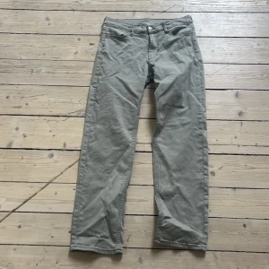 Ljusgrå jeans - Säljer ett par ljusgrå jeans med klassisk rak passform. Byxorna har fyra fickor, bälteshällor och stängs med dragkedja och knapp. Perfekta för en stilren och avslappnad look.