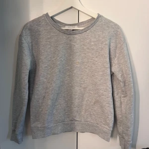 Ljusgrå sweatshirt - En enkel och stilren ljusgrå sweatshirt med rund halsringning och långa ärmar. Tvättas innan den skickas, så fläck inte medföljer. Storlek 32 men passar mig som bär Xs, från Primark.