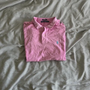 Rosa pikétröja från Ralph Lauren - Säljer en snygg rosa pikétröja från Ralph Lauren i storlek XL men sitter som M. Tröjan har en klassisk krage med knappar och det ikoniska broderade logotypen på bröstet. Perfekt för en stilren look!