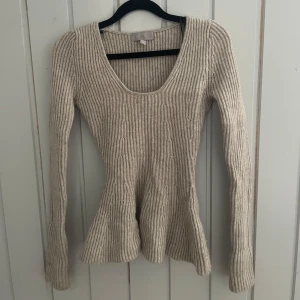 Beige figursydd stickad tröja - Säljer en beige ribbstickad tröja från H&M med lång ärm och djup rundad halsringning. Tröjan har en figurnära passform 💕