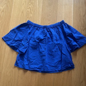 Blå offshoulder topp str s - Säljer en blå offshoulder topp med korta vida ärmar och resår vid halsen. Toppen är luftig och perfekt för varma dagar. Passar snyggt till både jeans och kjol.