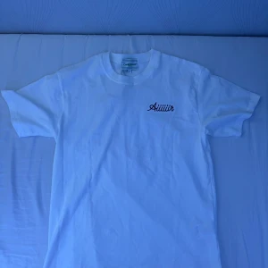 Vit Casablanca T-shirt (oanvänd) - (Pris kan diskuteras vid snabb affär) Vit t-shirt från Casablanca med trycket 'Aiiiiiir' på bröstet och stort grafiskt print med flygplansmotiv och logga på ryggen. Klassisk passform, rund hals och tillverkad i mjuk bomull. Perfekt för dig som gillar streetwear med en clean vibe.