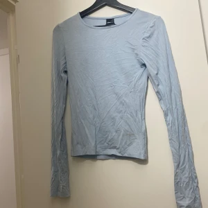 Ljusblå långärmad topp Gina Tricot XS - Enkel och stilren ljusblå långärmad topp från Gina Tricot i storlek XS. Tunn och mjuk bomullskänsla, perfekt för lager-på-lager. Rund halsringning och figurnära passform som funkar till många olika looks. Sminkfläkarna kommer tttas bort vid köp ville bara så fort som möjligt lägga upp en annons då toppen ej kommit till användning under ett halvår.