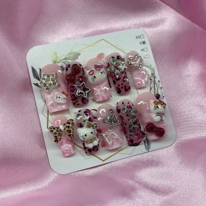 KittyLicious (S);Medium Square - Supergulliga gelé press-on naglar i rosa med leopardmönster, Hello Kitty-motiv och 3D-dekorationer som stjärnor, hjärtan, rosetter och pärlor. Mix av glansiga, med detaljer i silver och rött. Perfekt för dig som älskar unika och kreativa naglar. I storlek S: 15 mm, 11,5 mm, 12 mm, 11 mm, 9 mm 